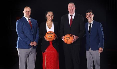 4 assistant coaches smile. 2 of them hold basketballs.